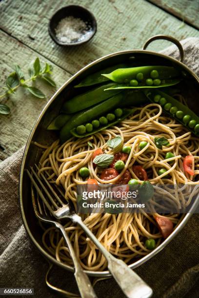 rustikale vollkorn-pasta mit frischen erbsen und tomaten - brycia james stock-fotos und bilder