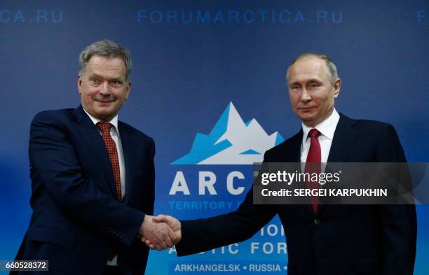 Russian President Vladimir Putin shakes hands with Finnish President Sauli Niinisto during their meeting as part of the International Arctic Forum in...