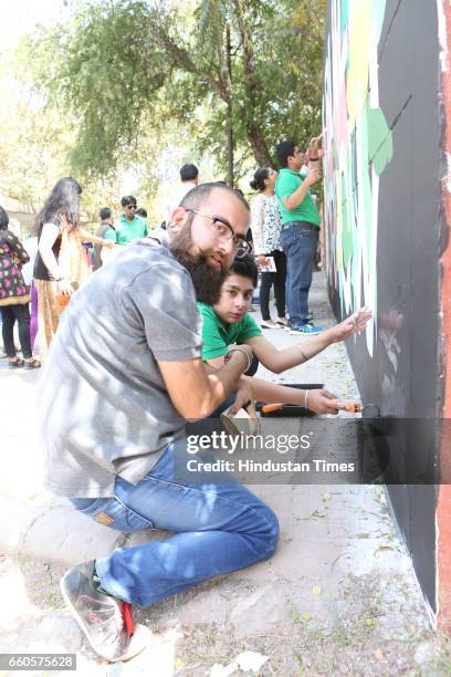 Over 40 underprivileged and differently-abled children from various NGOs and graffiti artists paint the phrase 'Let's Build Tomorrow' on a wall at...