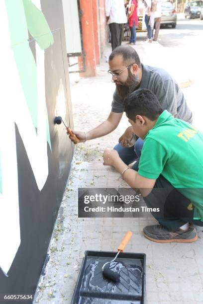 Over 40 underprivileged and differently-abled children from various NGOs and graffiti artists paint the phrase 'Let's Build Tomorrow' on a wall at...