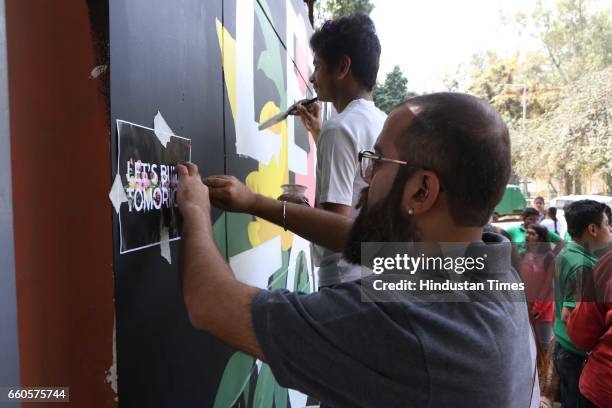 Over 40 underprivileged and differently-abled children from various NGOs and graffiti artists paint the phrase 'Let's Build Tomorrow' on a wall at...