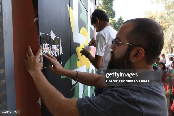 Over 40 underprivileged and differently-abled children from various NGOs and graffiti artists paint the phrase 'Let's Build Tomorrow' on a wall at...