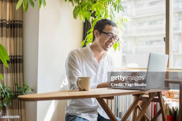 mid volwassen man aan het werk thuis op vakantie - male looking content stockfoto's en -beelden