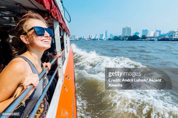 young woman explores city, looks out from river boat - tour boat stock pictures, royalty-free photos & images