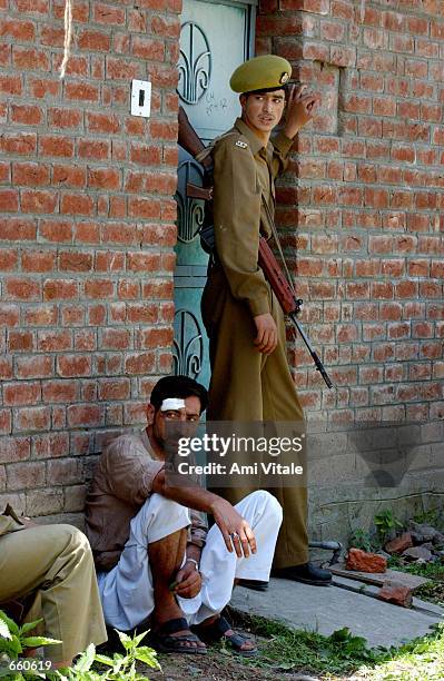 Kashmiri police officer stands next to an injured Kashmiri civilian during the funeral of Fayez Ahmed Lone on June 7, 2002 in Srinagar, the summer...