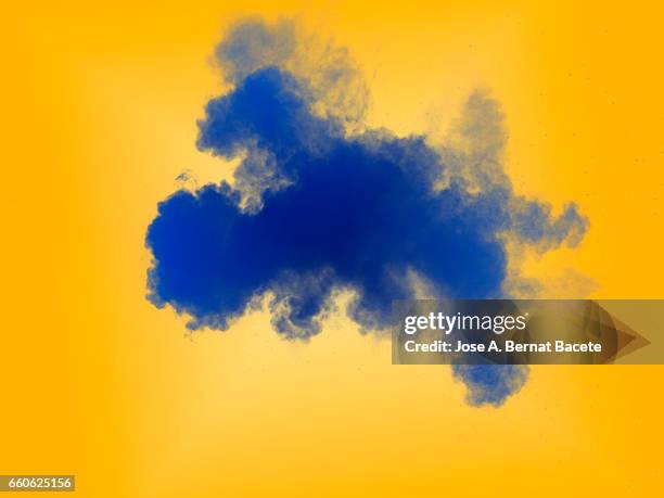 explosion of a cloud of powder of particles of  color blue e on a orange background - etéreo stockfoto's en -beelden