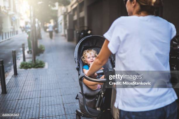 moeder met kinderwagen in stadswandeling - kinderwagen stockfoto's en -beelden