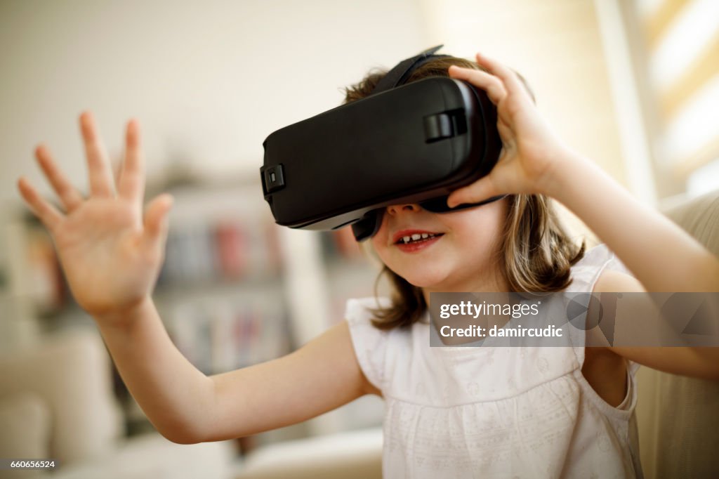 Little girl playing imaginary game with virtual reality headset