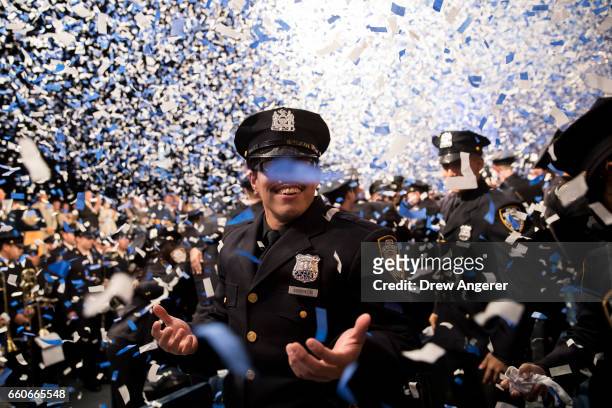 New member of the New York City Police Department smiles as confetti falls on him at the conclusion of the police academy graduation ceremony at the...