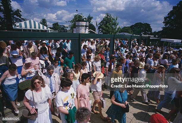 View of crowds of spectators making their way through the gates to watch play at the Wimbledon Lawn Tennis Championships at the All England Lawn...