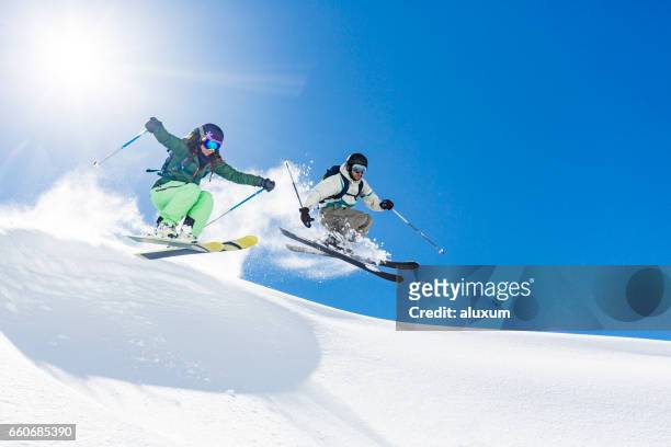frau und mann skifahren und springen - skifahren und snowboarden stock-fotos und bilder
