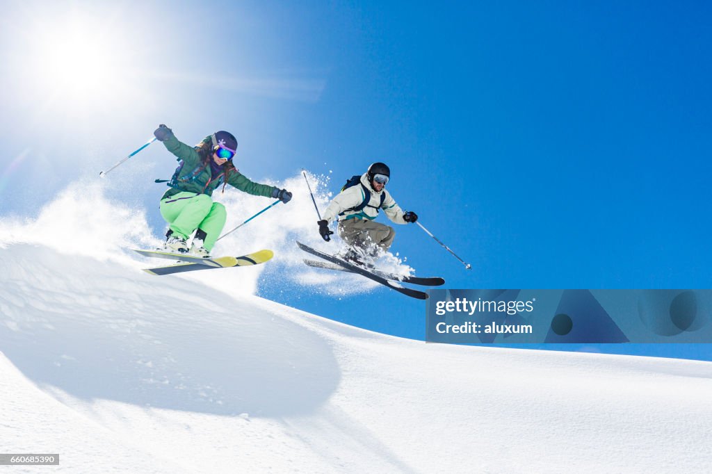 Kvinna och man skidåkning och hoppning