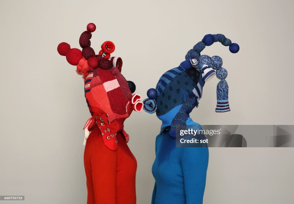 Two women wearing mask made of blue and red socks kissing,side view