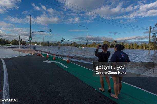 Local residents Christie and Haleigh McIntyre watches on as the Logan River near Beaudesert floods surrounding areas on March 31, 2017 in Brisbane,...