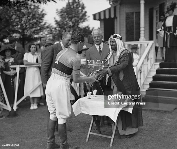 Alexis Mdivani , captain of the Los Diables polo team, receives the cup from Sheikh Ahmad Al-Jaber Al-Sabah , the Emir of Kuwait, after beating...