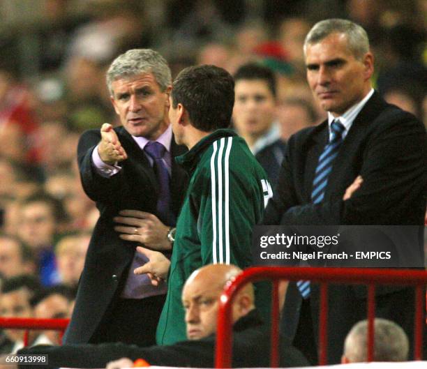 Wales' Manager Mark Hughes remonstrates with the fourth official Pascal Garibian while Poland's coach Pawel Janas looks on.