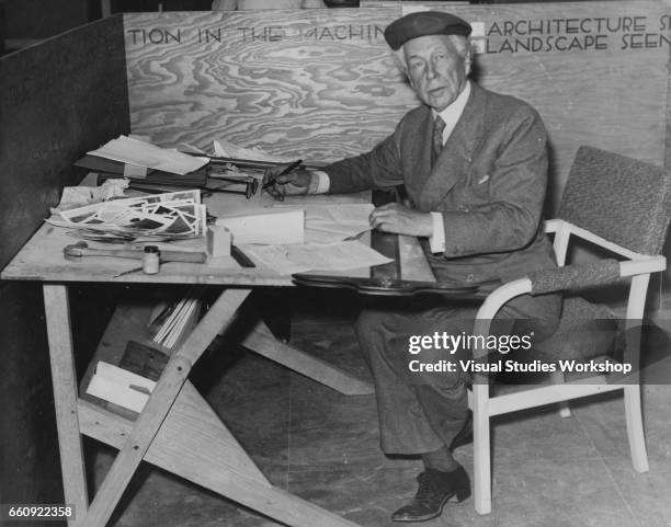 Portrait of American architect Frank Lloyd Wright as he poses at a drafting table during the Industrial Arts Exposition at Rockefeller Center Forum,...