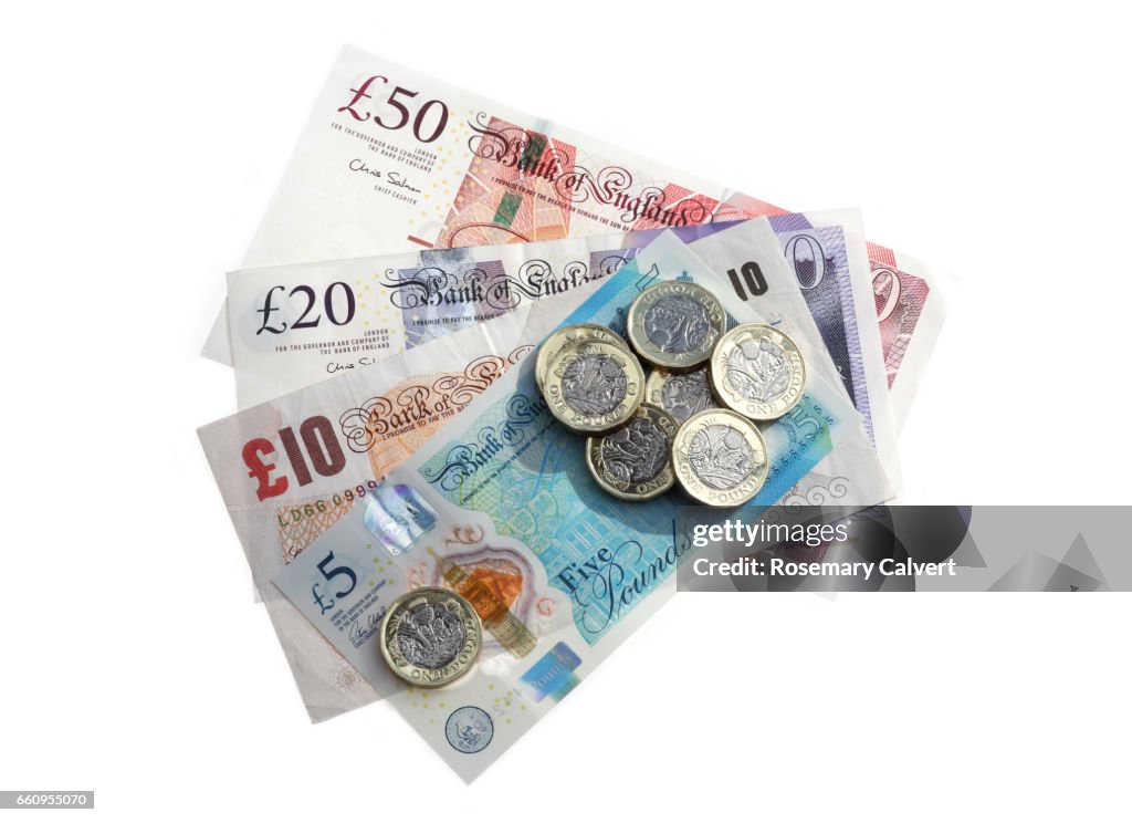 Different denominations of British pound notes with newly minted one pound coins.