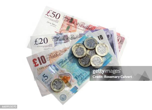 different denominations of british pound notes with newly minted one pound coins. - pond stockfoto's en -beelden