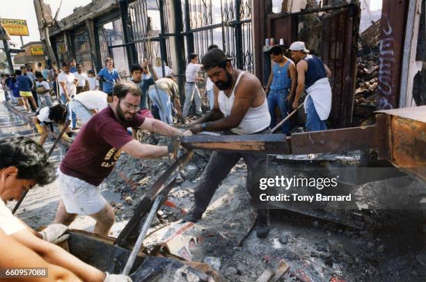 Tom Sedry and Arturo Pallacios were among those helping to clean up a building shared by a discount store and the Exposition Park Church of the...