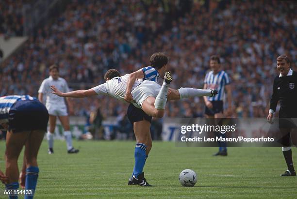 Tottenham Hotspur footballer Clive Allen is lifted and held in the air by Coventry City player Trevor Peake to the amusement of referee Neil Midgley...