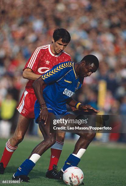 Alan Hansen of Liverpool tries to block John Fashanu of Wimbledon from advancing with the ball during a first division game between Wimbledon and...