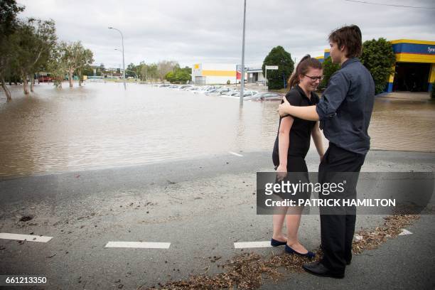 Maddie Skyring is comforted by a companion after discovering her submerged car at the flooded Beenleigh train station carpark, on March 31, 2017. -...
