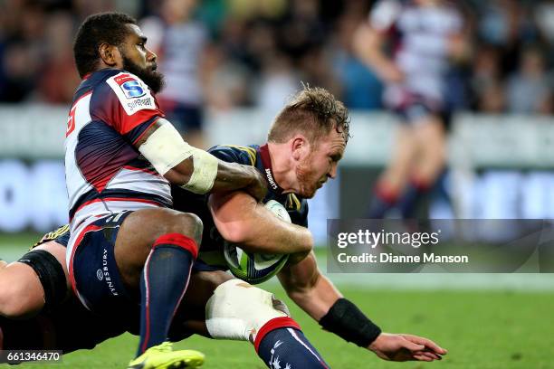 Gareth Evans of the Highlanders dives over to score a try while in the tackle of Marika Koroibete of the Rebels during the round six Super Rugby...