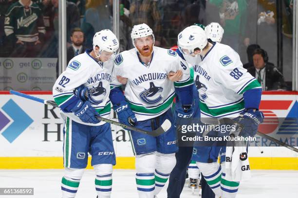 Nikolay Goldobin and Nikita Tryamkin help their Vancouver Canucks teammate Jack Skille off the ice after he sustains an injury during the game...