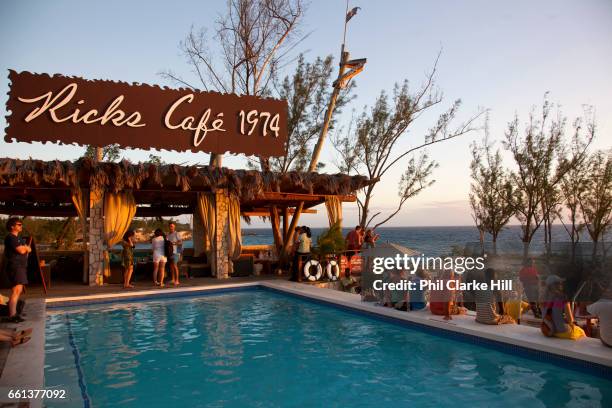 People sit around a pool in the afternoon light, Ricks Cafe, Negril, Jamaica. .