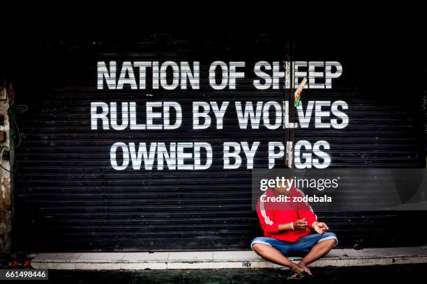 man sitting in front of a closed store in khao san road, bangkok - thailandia stock pictures, royalty-free photos & images