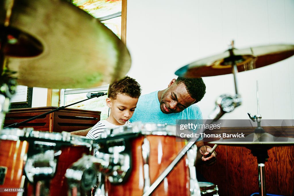 Father teaching young son to play drums