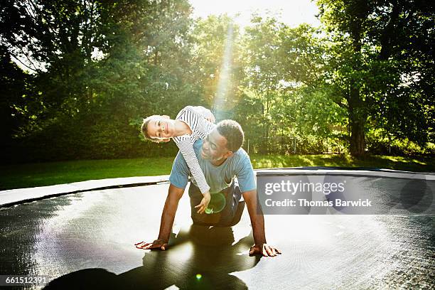 smiling boy on fathers back while playing - smiling controluce foto e immagini stock