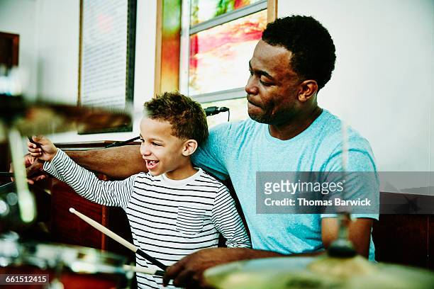 Smiling young boy playing drums with father