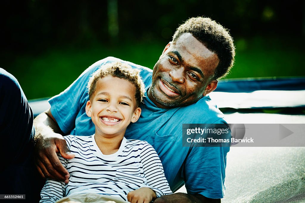 Laughing young boy leaning against father