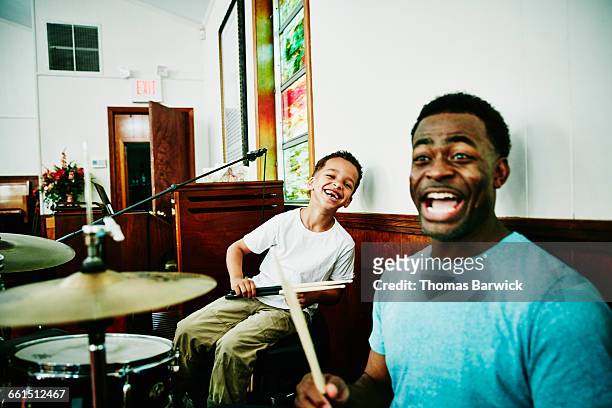 Laughing father and son playing on drum set