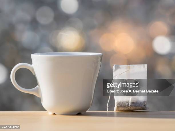 cup on a table to prepare an infusion of grasses of tea (tea bag ),  illuminated by the light of the sun - nivel de superficie stock pictures, royalty-free photos & images