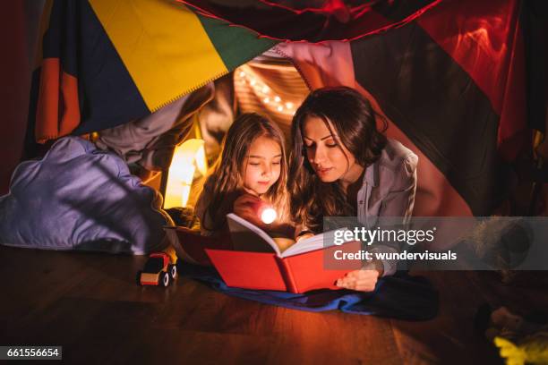 mother reading a book to her daughter at night - fairytale house stock pictures, royalty-free photos & images