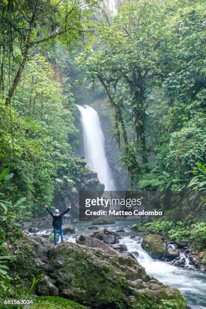 tourist looking at waterfall in the green rainforest of costa rica - costa rica waterfall stock pictures, royalty-free photos & images