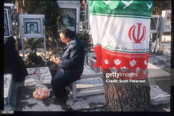 Man and woman sit at a grave February 6, 1999 in Tehran, Iran. Thousands went to the tombs of those killed during the Revolution and the Iran-Iraq...