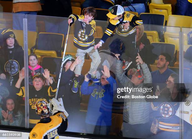 Bruins fans are held up against the glass at the end of the game as one is lucky enough to get a stick from Bruins goalie Tuukka Rask. The Boston...