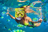 Girl in snorkeling mask dive underwater with coral reef fishes