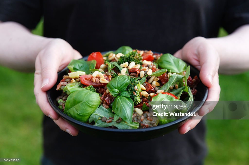 Hands holding bowl with prepared rice salad