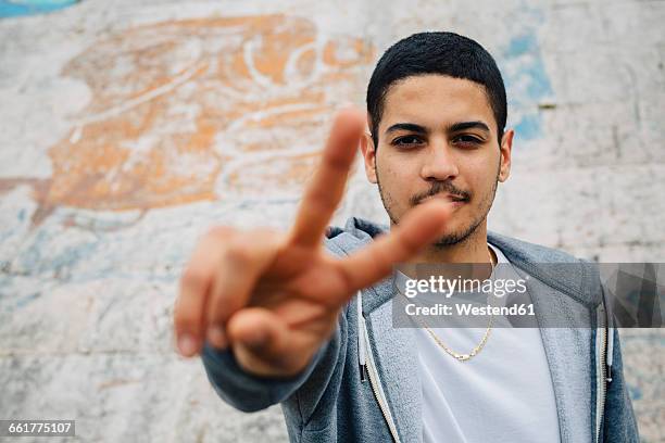 young man showing victory sign - victory sign stock-fotos und bilder