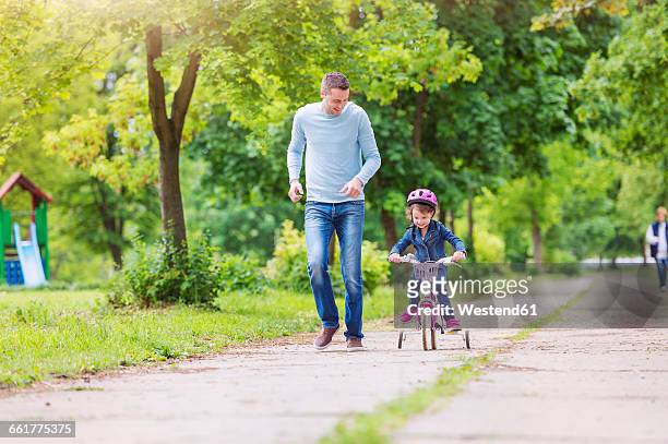 father accompanying daughter on bike - training wheels stock pictures, royalty-free photos & images