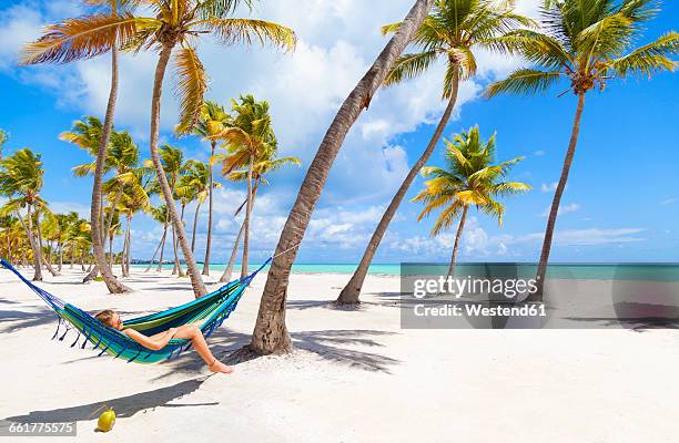 dominican rebublic, young woman lying in hammock on tropical beach - hängematte stock-fotos und bilder