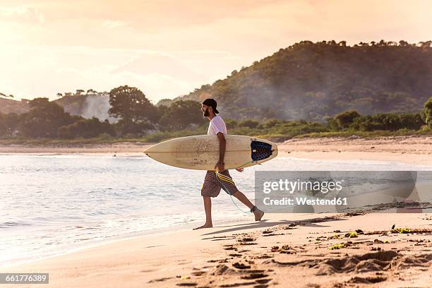 indonesia, sumbawa island, surfer on a beach in the evening - sumbawa foto e immagini stock