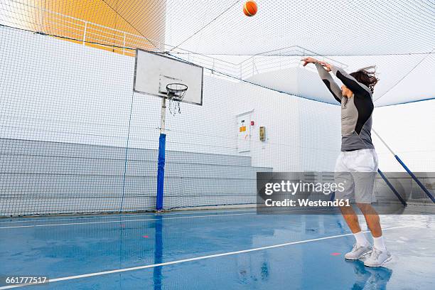 young man playing basketball on a deck of a cruise ship - basketball net stockfoto's en -beelden
