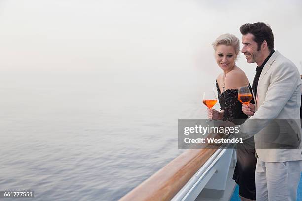 couple with aperitive leaning on railing of a cruise liner - cruise liner foto e immagini stock