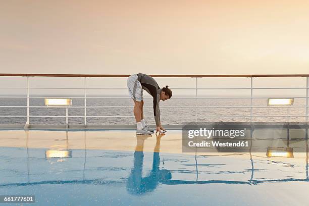 young man doing exercises on a shipdeck, cruise ship, mediteranean sea - かがむ 人 横 ストックフォトと画像